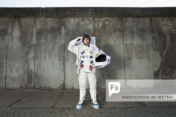 Ein salutierender Astronaut  der auf einem Bürgersteig in einer Stadt steht.