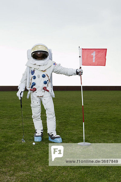 Ein Astronaut  der auf einem Putting Green posiert.