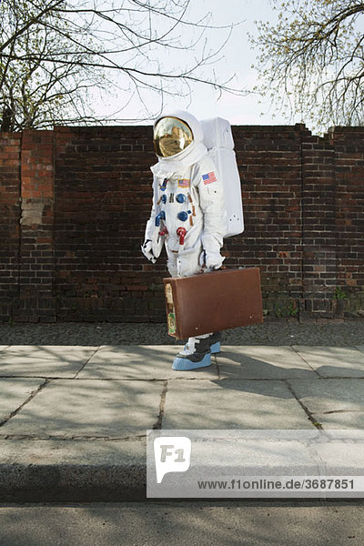 Ein Astronaut  der einen Koffer trägt und auf dem Bürgersteig der Stadt läuft.