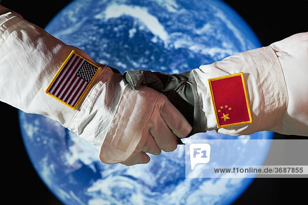 Ein amerikanischer Astronaut schüttelt einem chinesischen Astronauten die Hand.