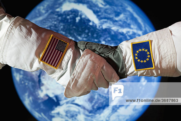 Ein amerikanischer Astronaut  der einem Astronauten aus der Europäischen Union die Hand schüttelt.