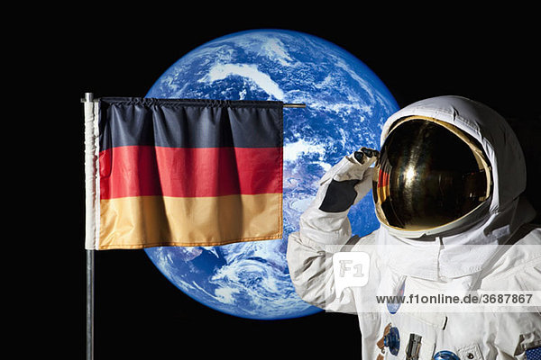 Ein Astronaut grüßt eine deutsche Flagge mit der Erde im Hintergrund.