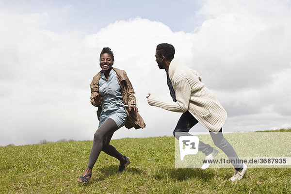 Ein junger Mann jagt seine Freundin einen Hügel hinunter.