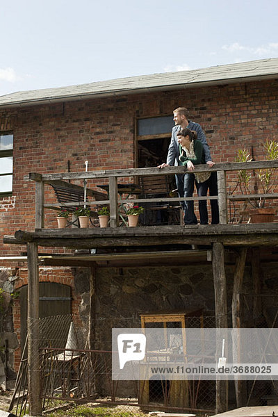 Ein Paar steht auf einem Balkon und schaut in die Ferne.