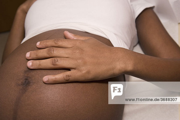 Eine schwangere Frau auf einem Untersuchungstisch liegend  Mittelteil