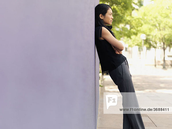 A businesswoman leaning against a wall