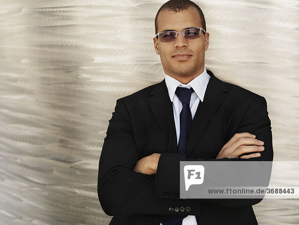 Porträt eines Geschäftsmannes mit gekreuzten Armen und Sonnenbrille