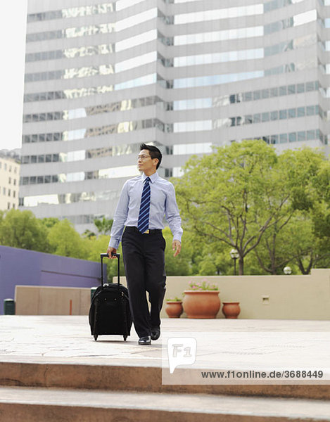 A businessman pulling a rolling suitcase