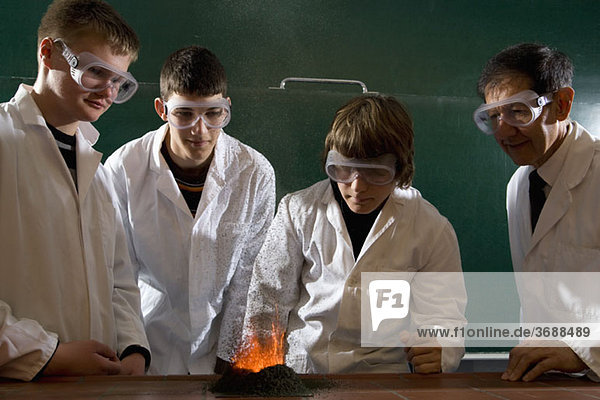 Ein Lehrer  der Schüler bei einem Chemie-Experiment mit angezündetem Schießpulver beaufsichtigt.