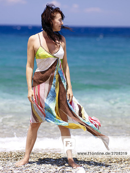 Frau mit wehendem Strandkleid vor türkisfarbenem Meer am Strand von Samos in der östlichen Ägäis  Griechenland  Europa