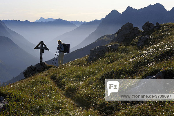 Bergsteigerin vor Gedenkkreuz im Morgenlicht  Hinterhornbach  Lechtal  Außerfern  Tirol  Österreich  Europa