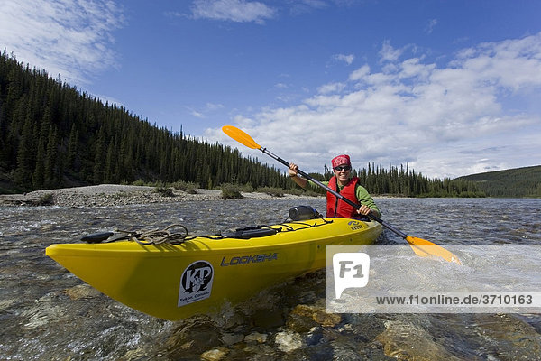 Young woman in kayak  paddling  kayaking  clear  shallow water of upper Liard River  Yukon Territory  Canada