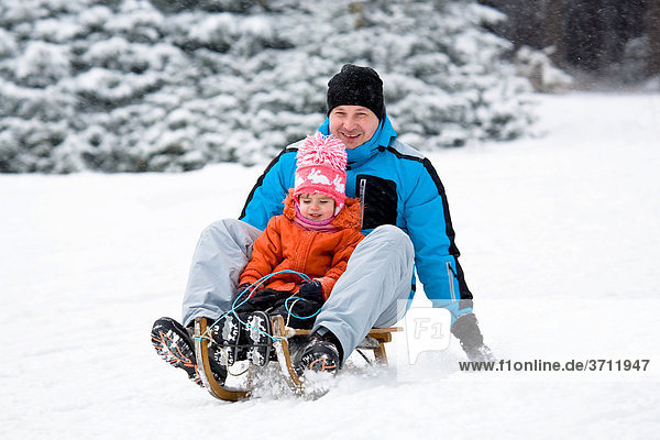 Sledding father and daughter