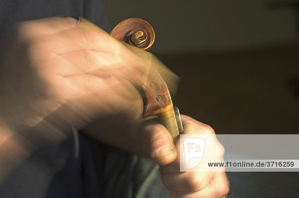 Violin maker is working at the scroll of a violin