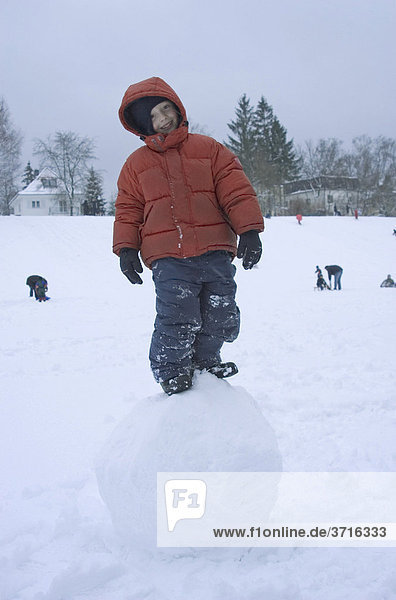 Six Year old boy standing on big snowball