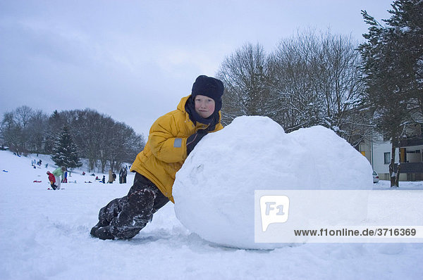 8-jähriger Junge rollt große Schneekugel
