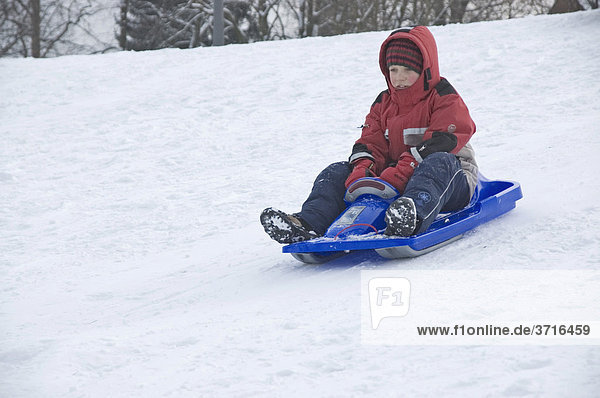 A child is sledging down a hilll