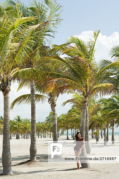 Junge Frau am Strand bei Palme