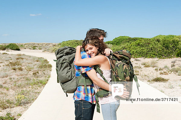 Young couple wearing backpacks embracing