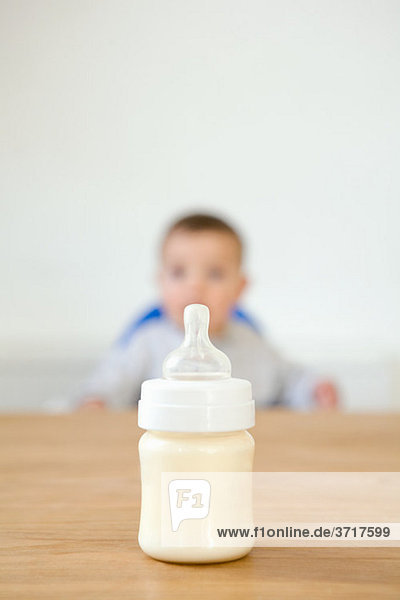 Babyflasche im Vordergrund und Baby im Hintergrund