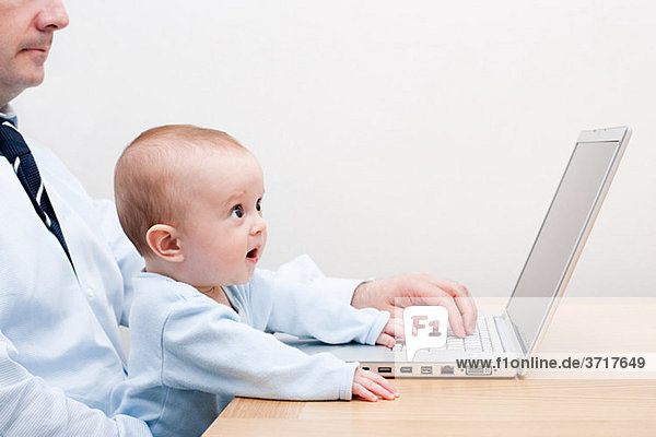 Arbeitender Vater und Baby am Laptop