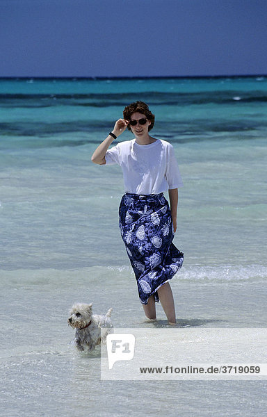 Junge Frau mit kleinem Hund an einem Strand auf Mallorca  Spanien