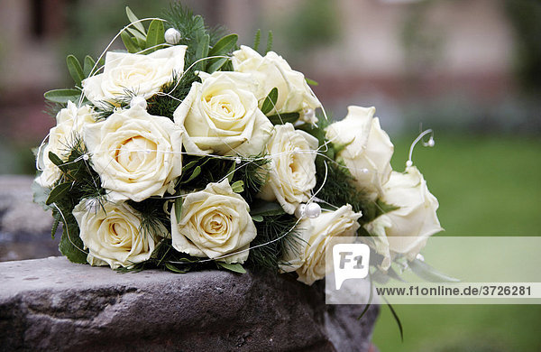 Bridal bouquet with white roses on the edge of a fountain