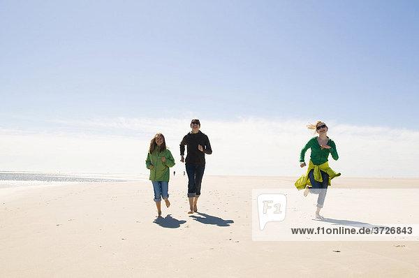 Junge Frau und zwei Jugendliche laufend und lachend am Strand  Amrum  Nordsee  Deutschland  Europa