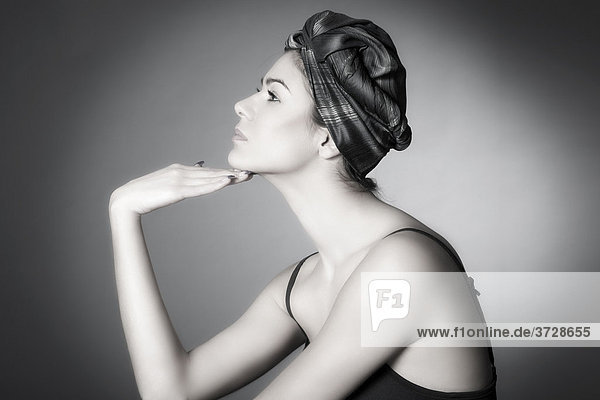 Junge dunkelhaarige Frau  mit Kopftuch hält Hand an Kinn  seitliches Portrait
