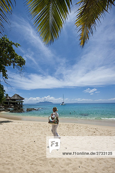 Woman walking on a beach near Glacis  Mahe Island  Seychelles  Indian Ocean  Africa