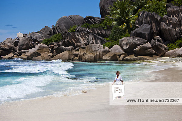 Woman running on the beach of Grand Anse  with the typical granite rocks of La Digue  Indian Ocean  La Digue Island  Seychelles  Indian Ocean  Africa