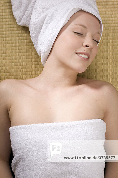 Junge Frau entspannt bei Wellness mit Handtuch um den Kopf
