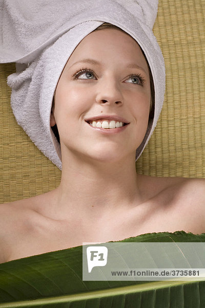 Junge Frau entspannt bei Wellness mit Handtuch um den Kopf