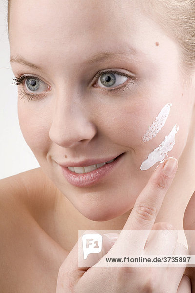 Young woman applying face cream