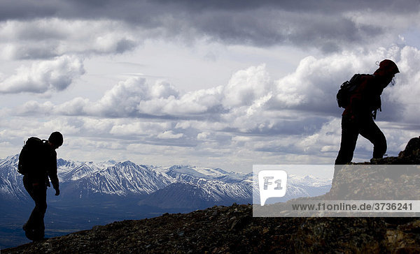 Silhouette zweier junger Frauen beim Wandern  Berg Mt. Lorne und Berge des Pacific Coast Gebirges dahinter  Yukon Territory  Kanada  Nordamerika