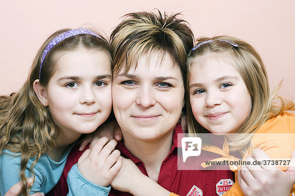 Smiling mother  36 years old  with her two daughters  10 and 6 years old  indoors