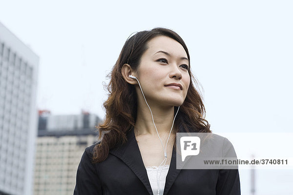 Young Asian woman  iPod  listening to music  business  Tokyo  Japan  Asia