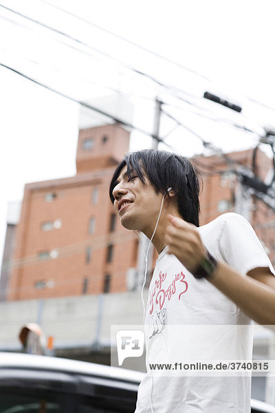 Junger Mann hört Musik  iPod  MP3 Player  Tokyo  Japan  Asien