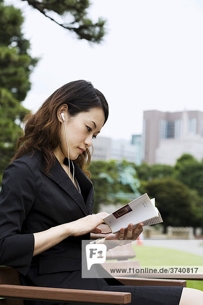 Junge Asiatin liest ein Buch im Park  Tokyo  Japan  Asien
