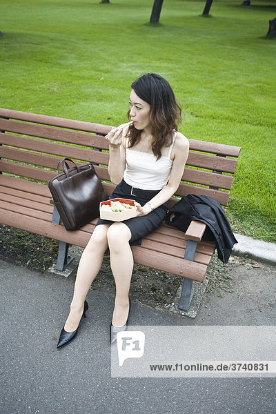 Young woman eating lunch in a park  Tokyo  Japan  Asia