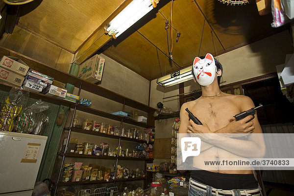 Young man wearing a mask and holding two pistols in a shop  Tokyo  Japan  Asia