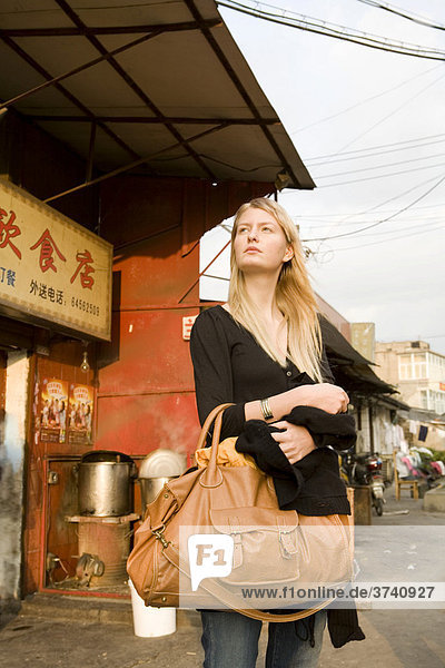 Junge Frau steht auf einer Straße  Shanghai  China  Asien