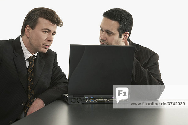 Zwei Geschäftsleute sitzen hinter einem Laptop