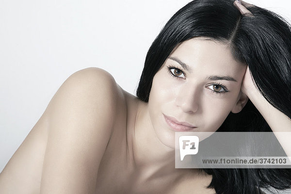 Dark haired young woman supporting her head on her hand  portrait