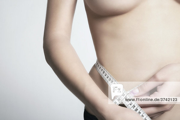 Slim woman measuring her waist with a tape measure