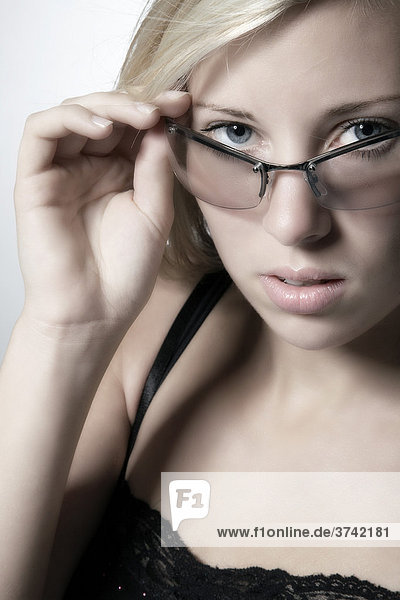 Junge blondhaarige Frau schaut über Brillenrand  Portrait
