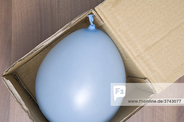 Light-blue balloon in a cardboard box