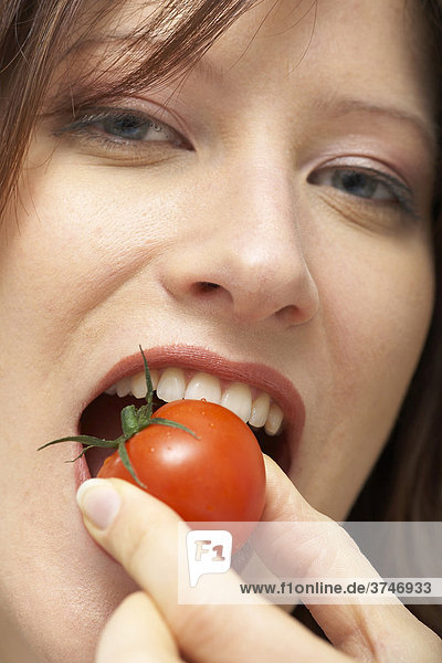 Frau beißt in Cherry Tomate