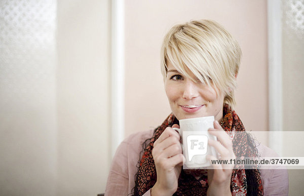 Young woman with short blonde hair drinking coffee