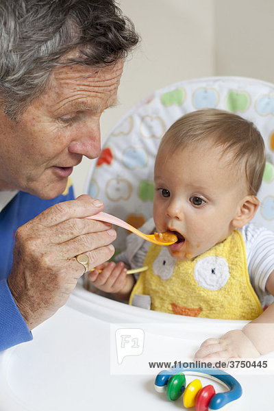 Grandad feeding grandson with baby spoon